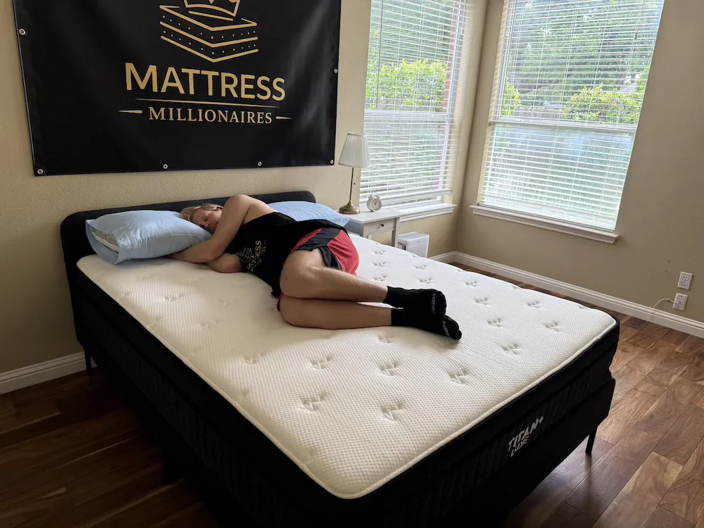 Tester lying on their side with knees bent on the Titan Plus Luxe mattress