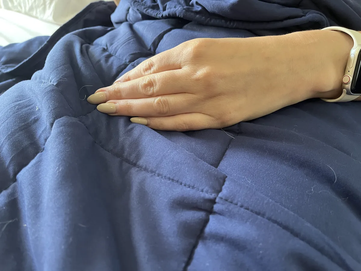 Close-up of a hand resting on a weighted blanket showing even pressure distribution