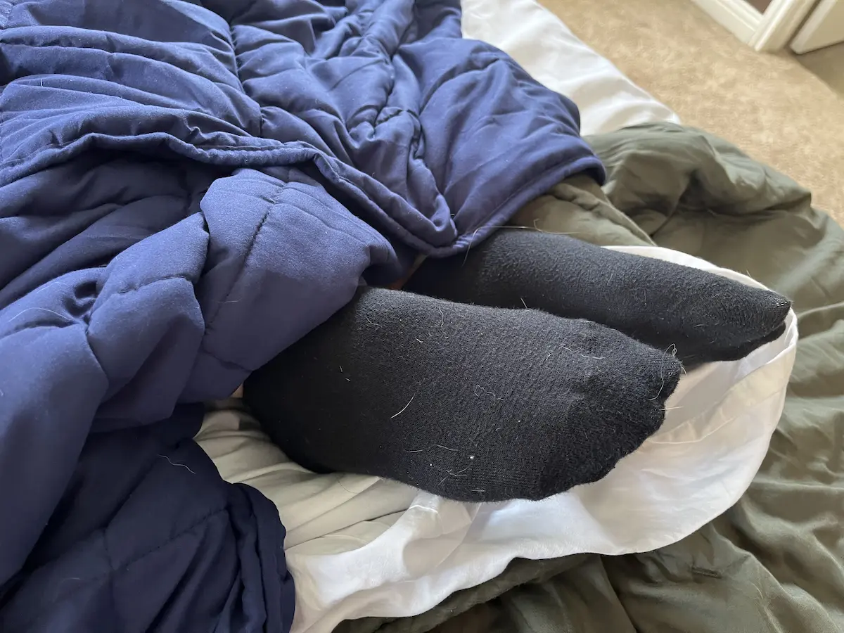 Feet sticking out from beneath a weighted blanket to cool down