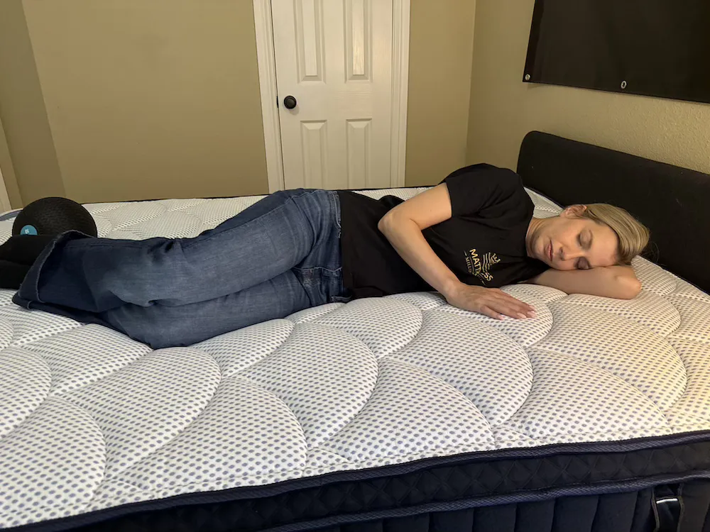 Woman lying on her side on a quilted pillow-top mattress with her head resting on her bent arm