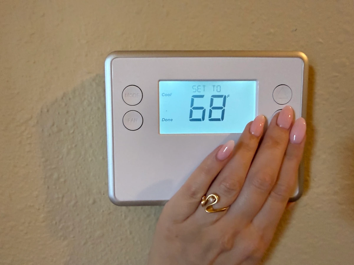 Image of a hand on a thermostat
